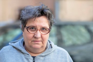 Kameraya bakan kızgın, yaşlı bir kadının portresi. Yaşlı yaşlı bayan vatandaş hoşnutsuz, dışarıda üzgün. Mutsuz emeklilik kavramı.