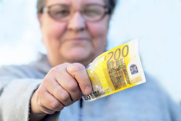 Satisfait, Une femme âgée adulte donne une monnaie de gros plan 200 euros. Femme mûre et tient une facture. Femme âgée. Concept Pensionnés retraités et argent . — Photo