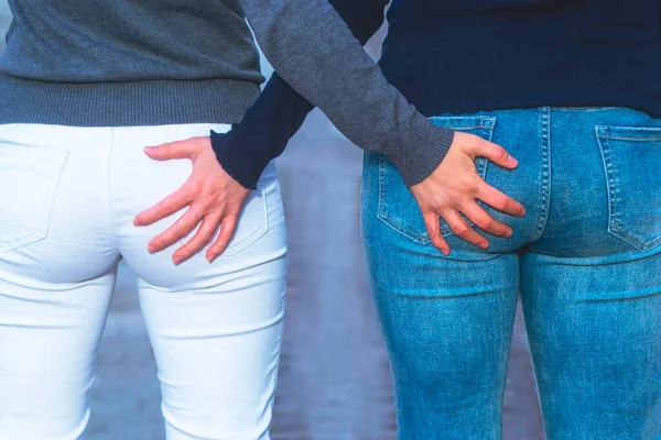 young girls hold touch each other. Women hold hands on fanny, ass, close up. The concept of same-sex relationships, LGBT people, lisbians