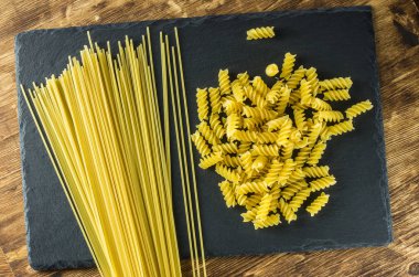 Spagetti ve makarna spiraller üstten görünüm arduvaz arka plan üzerinde.