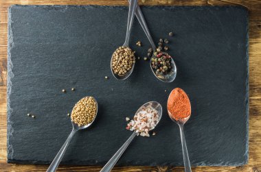 kaşık beş baharat kayrak ve hardal karabiber tuz kişniş ahşap bir yüzey üzerinde yatıyordu