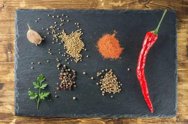 kırmızı sıcak biber biber, baharatlar, hardal, kişniş, maydanoz, sarımsak, tahta siyah arduvaz ve ahşap tahta Üstten Görünüm