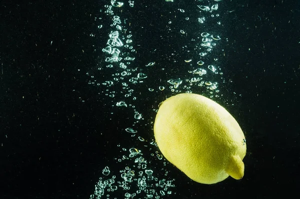 Zitrone im Wasser auf schwarzem Hintergrund — Stockfoto