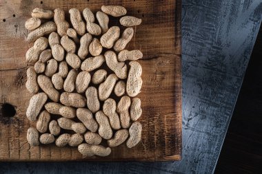 Çatlaklarla, çiziklerle ve beton yüzeydeki deliklerle dolu eski bir tahtanın üzerinde bir sürü kabuklu fıstık bulunur..