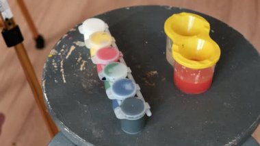 Anaokulu çocuğu sehpaya fırçayla guaj boyası çiziyor. Arkadan vurulmuş. 4k