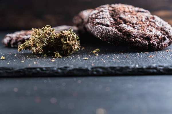 Schokoladenkekse mit Marihuana, bestreut mit Schokoladenchips und Cannabis, befinden sich auf einem Schieferteller. — Stockfoto