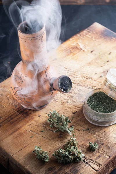 Oude bong en open molen cannabis en marihuana in rook bevinden zich. Verticale samenstelling — Stockfoto