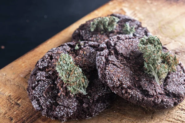 Tres galletas de chocolate con marihuana se encuentran en un plato de madera — Foto de Stock