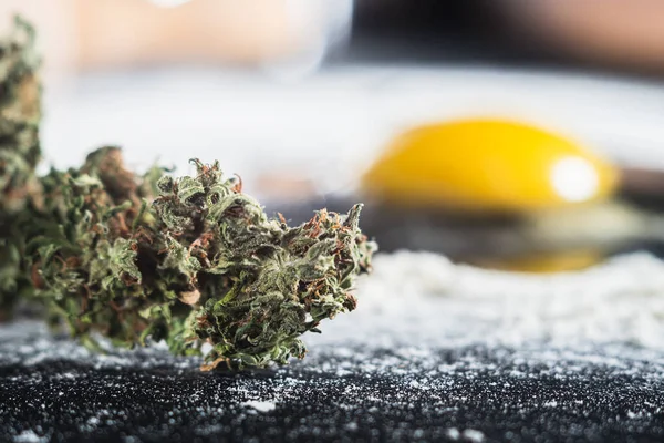 Den Prozess der Herstellung von Cannabis-Gebäck. rohe zerbrochene Eier, Nudelholz, Mehl und getrocknete Marihuana-Blütenstände. — Stockfoto
