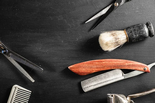 Ciseaux de coiffure vintage manuel tondeuse peigne brosse rasoir dangereux sont sur une surface poussiéreuse noire . — Photo