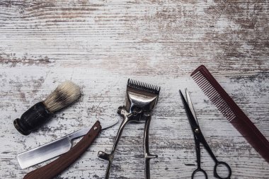 Klasik berber aletleri tehlikeli jilet kuaför makas eski manuel kırpıcı tarak tıraş fırçası. Eski beyaz yıpranmış ahşap arka plan.