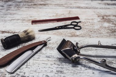 Klasik berber aletleri tehlikeli jilet kuaför makas eski manuel kırpıcı tarak tıraş fırçası. Eski beyaz yıpranmış ahşap arka plan.