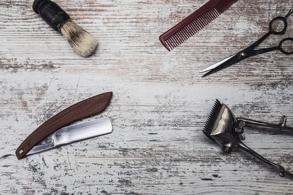 Klasik berber aletleri tehlikeli jilet kuaför makas eski manuel kırpıcı tarak tıraş fırçası. Eski beyaz yıpranmış ahşap arka plan.