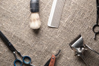 vintage barber tools dangerous razor hairdressing scissors old manual clipper comb shaving brush. on sackcloth background.