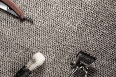 vintage barber tools dangerous razor hairdressing scissors old manual clipper comb shaving brush. on sackcloth background.