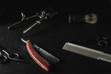 Siyah arka planda klasik berber malzemeleri. Profesyonel kuaför aletleri. Makas, manuel saç kesme makinesi, jilet, tıraş fırçası, tarak