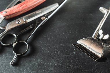Siyah arka planda klasik berber malzemeleri. Profesyonel kuaför aletleri. Makas, manuel saç kesme makinesi, jilet, tıraş fırçası.