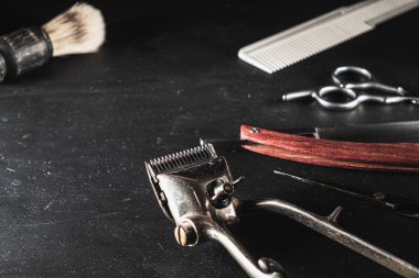 Siyah arka planda klasik berber malzemeleri. Profesyonel kuaför aletleri. Makas, manuel saç kesme makinesi, tıraş fırçası, tarak. Boşluğu kopyala
