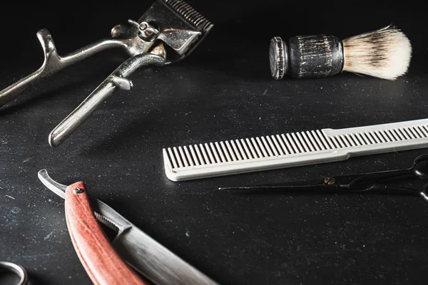 Équipement vintage salon de coiffure sur fond noir. Outils professionnels de coiffure. ciseaux, tondeuse manuelle, rasoir, brosse à raser, peigne — Photo