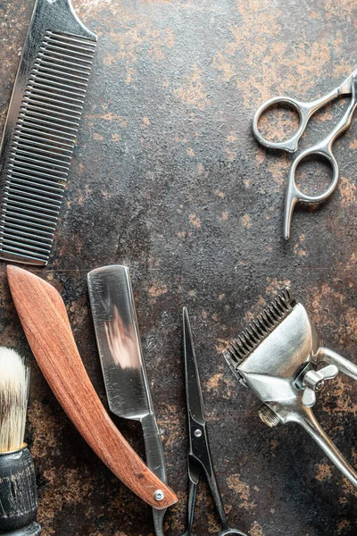 vintage barber tools dangerous razor, hairdressing scissors, old manual clipper, metal comb, shaving brush. old rusty metal background. Vertical orietetion. top view, flat lay.