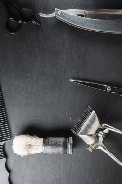 Siyah tozlu bir yüzeyde eski berber aletleri vardır. Klasik manuel saç kesme makinesi tıraş fırçası tıraş fırçası tıraş fırçası saç kesme makası. siyah monokrom. Dikey. Üst Manzara. düz yat.