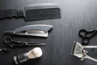 Siyah tozlu bir yüzeyde eski berber aletleri vardır. Klasik manuel saç kesme makinesi tıraş fırçası tıraş fırçası tıraş fırçası saç kesme makası. yatay üst görünüm düzlüğü