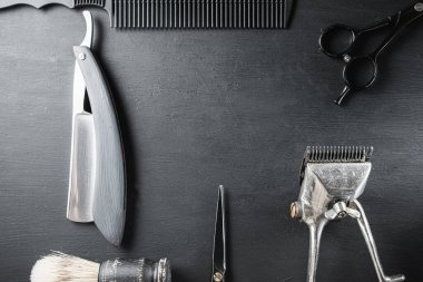 Siyah tozlu bir yüzeyde eski berber aletleri vardır. Klasik manuel saç kesme makinesi tıraş fırçası tıraş fırçası tıraş fırçası saç kesme makası. siyah monokrom. Yatay. Üst Manzara. düz yat.