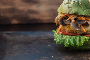 Bir parça vejetaryen burger. marul, pirzola vejetaryen et alternatifleri nohut mısır patatesi, kızarmış soğan ve havuçtan oluşur. Kızarmış soğan ve havuçlu mantar. Paslı pişirme çubuğu. Ahşap arka plan. çoklu uzay. yatay yönelim.