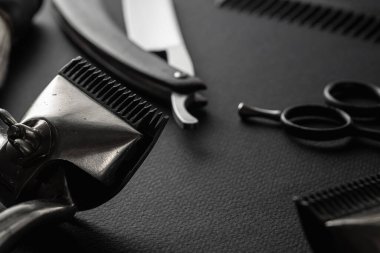 Siyah bir yüzeyde eski berber aletleri vardır. İki klasik manuel saç makası, jilet, tarak, tıraş fırçası, kuaför makası. siyah monokrom. yatay yönelim.