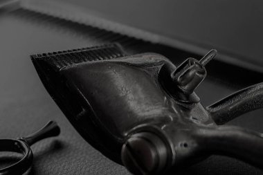 Siyah bir yüzeyde eski berber aletleri vardır. Klasik manuel saç makası, kuaför makası. siyah monokrom. düşey yönelim.