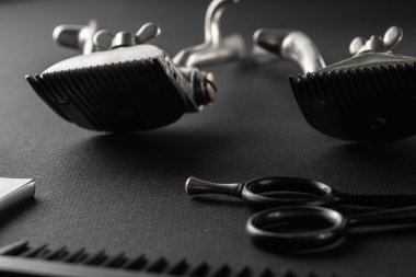 Siyah bir yüzeyde eski berber aletleri vardır. Klasik manuel saç makasi, ustura, tarak, kuaför makasi. siyah monokrom. yatay yönelim.