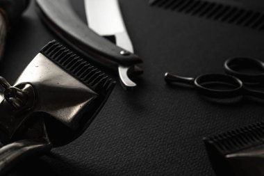 Siyah bir yüzeyde eski berber aletleri vardır. İki klasik manuel saç makası, jilet, tıraş fırçası, kuaför makası. siyah monokrom. yatay yönelim.