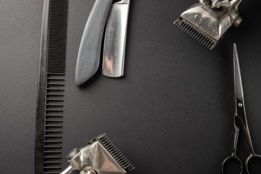 Siyah bir yüzeyde eski kuaför aletleri vardır. İki klasik el yapımı saç makası, tarak, jilet, kuaför makası, tıraş fırçası. siyah monokrom. yatay yönelim.