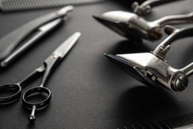 Siyah yüzey eski berber aletleridir. İki klasik manuel saç makası, tarak, jilet, tıraş fırçası, kuaför makası. siyah monokrom. düşey yönelim.