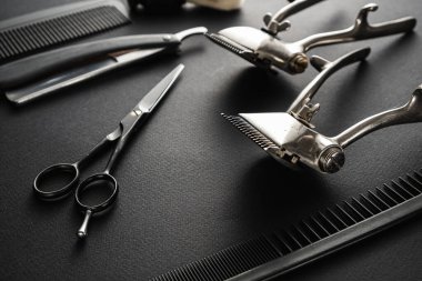 Siyah bir yüzeyde eski berber aletleri vardır. İki klasik manuel saç makası, tarak, jilet, tıraş fırçası, kuaför makası. siyah monokrom. yatay yönelim.