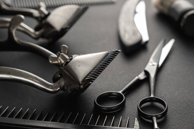 Siyah yüzey eski berber aletleridir. İki klasik manuel saç makası, tarak, jilet, tıraş fırçası, kuaför makası. siyah monokrom. düşey yönelim.