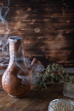 Duman bongu. Açık öğütücü ve marihuana. Ahşap bir yüzeyde kenevir. Tahta tepside boyayla boyanmış. Boşluğu kopyala .