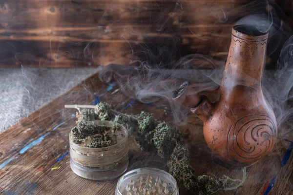 Rauchbong. offene Mühle mit Marihuana. Cannabis auf einer Holzoberfläche. auf einem mit Farbe befleckten Holztablett. horizontal. Kopierraum übrig . — Stockfoto