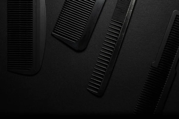 On a black surface are old barber tools. barber tools. four comb. black monochrome. frame. top view flate lay.