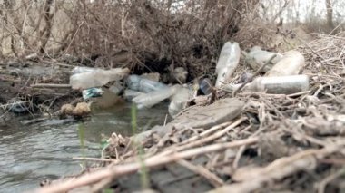Ekolojik felaket. Bahar temizliği deresi plastik çöp şişeleriyle kirlenmiş. 4k