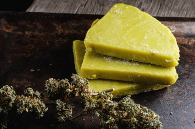 Eski paslı metal damlayan tavada rustik kenevir yağı ve tıbbi marihuana tomurcuğu. Eski ahşap arka plan. yatay oryantasyon. yakın plan.