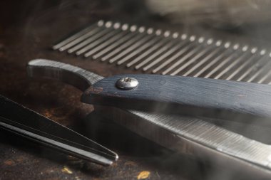 Paslı bir yüzeyde eski kuaför aletleri vardır. Makas, tarak, jilet, yaklaşın. Kırsal kesim. yatay oryantasyon. kopyalama alanı. buharlı araçlar.