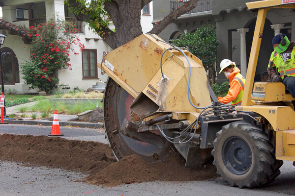 Аламеда, Калифорния - 07 ноября 2019 года: экипажи срезают канаву посреди жилой улицы до подземных линий для уличного освещения. Подземные работы имеют решающее значение в зонах повышенного пожарного риска
.