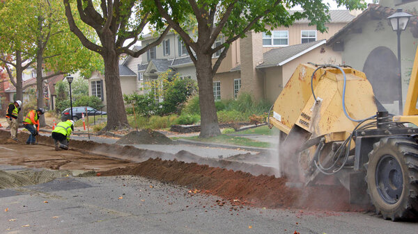 Аламеда, Калифорния - 07 ноября 2019 года: экипажи срезают канаву посреди жилой улицы до подземных линий для уличного освещения. Подземные работы имеют решающее значение в зонах повышенного пожарного риска
.