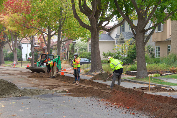 Аламеда, Калифорния - 07 ноября 2019 года: экипажи срезают канаву посреди жилой улицы до подземных линий для уличного освещения. Подземные работы имеют решающее значение в зонах повышенного пожарного риска
.