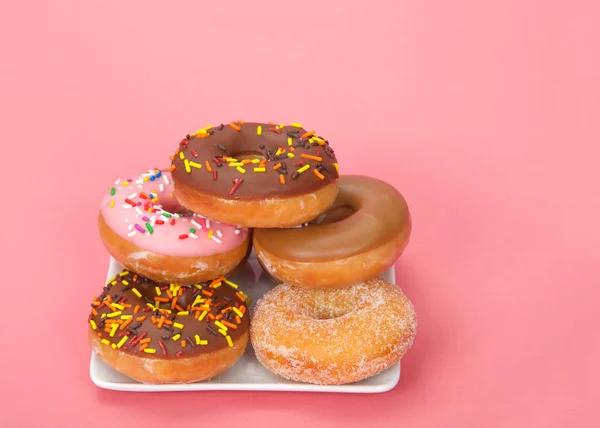 Kleiner Quadratischer Teller Mit Gestapelten Donuts Verschiedene Geschmacksrichtungen Rosa Hintergrund — Stockfoto