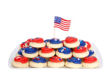 Kırmızı ve mavi şekerle kaplanmış, üzeri şeker parçacıklarıyla kaplı vatansever şekerli kurabiyelerle dolu dikdörtgen porselen bir tabak. Üstünde Amerikan bayrağı kürdanı var. Beyazda izole edilmiş.