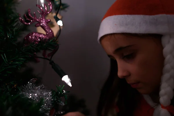 Närbild av flicka klädd som jultomten upplyst med julgran ljus. — Stockfoto