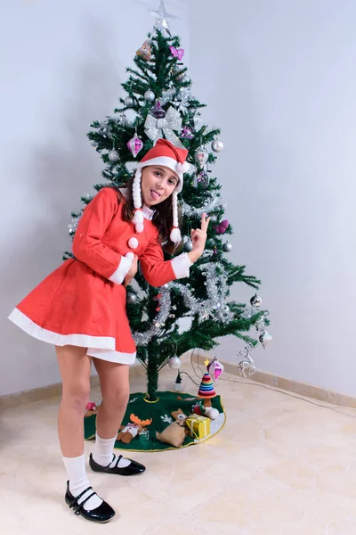 Retrato de niña vestida de Santa Claus junto al árbol de Navidad . — Foto de Stock