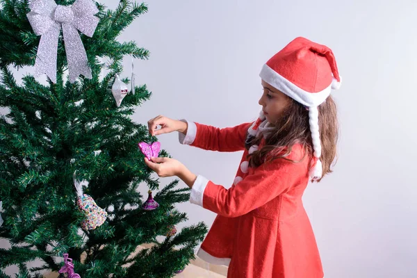 装饰圣诞树的小女孩。 装扮成圣诞老人. 图库图片